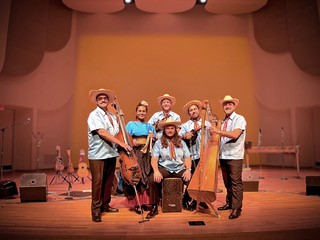 Image of six performers on a stage holding instruments.